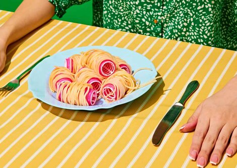 Dame am Esstisch mit Teller gefüllt mit Spaghetti auf Lockenwickler | © shutterstock