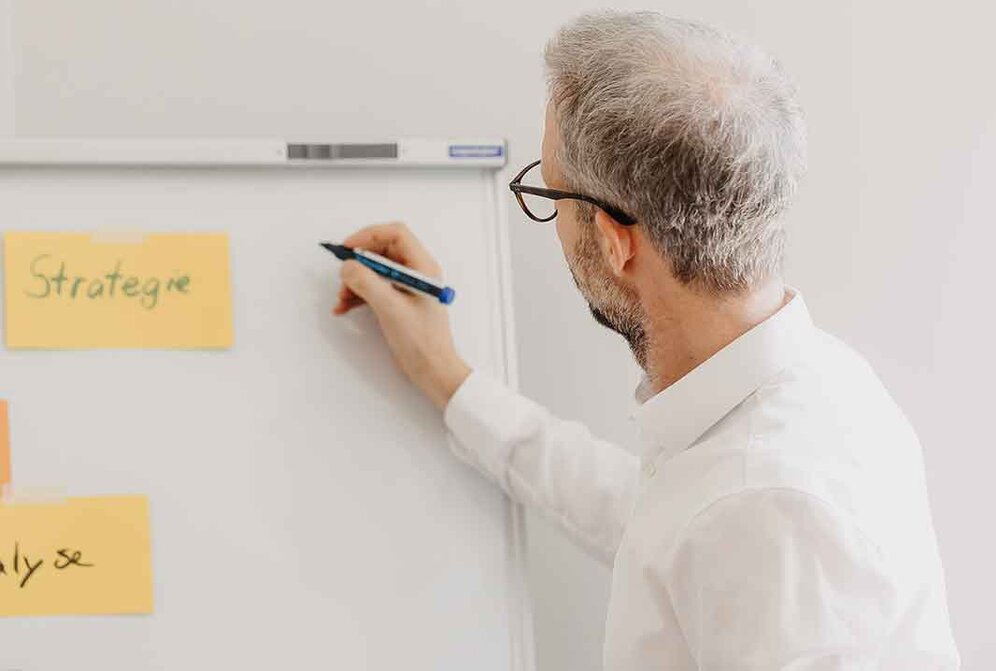 Jemand schreibt auf einem Whiteboard | © Nadine Christine Photography