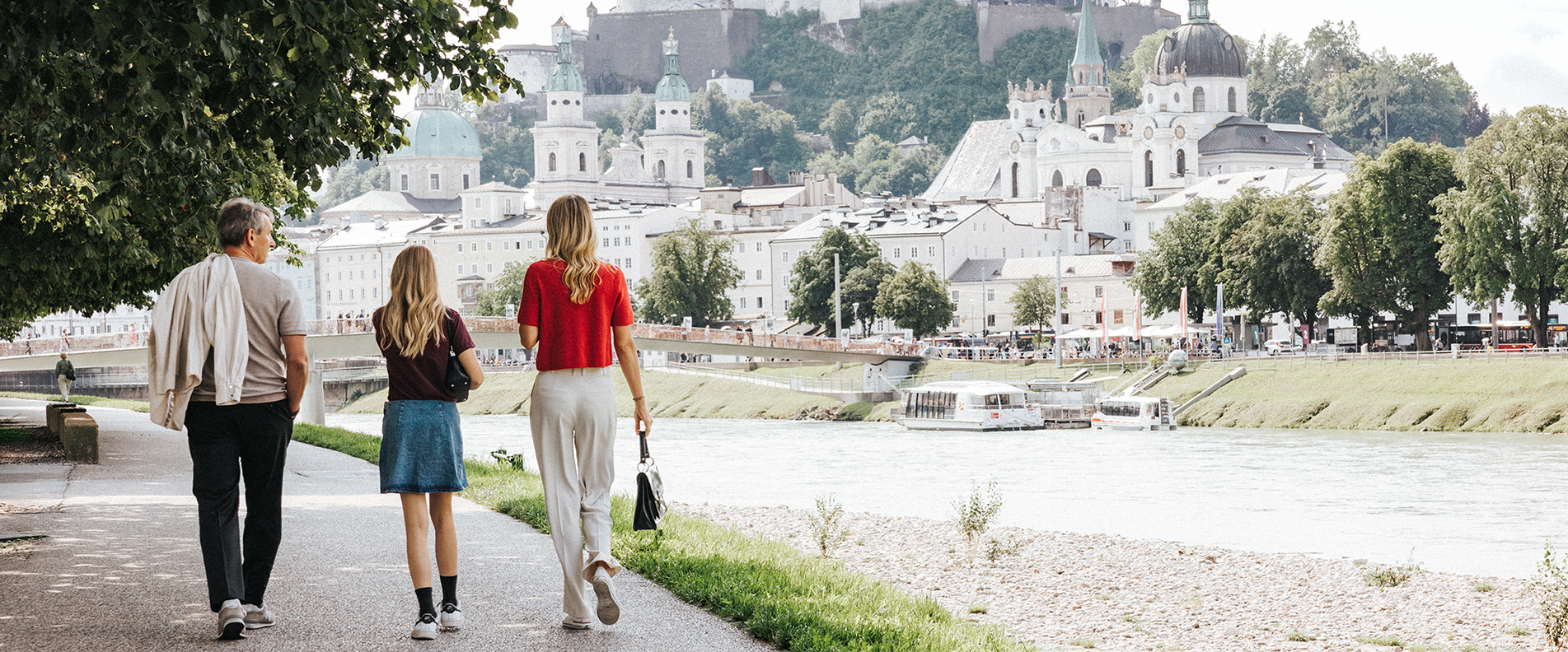Eine Familie spaziert der Salzach entlang in die Altstadt Salzburg | © Niko Zuparic
