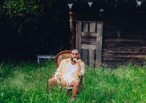 Ein Musiker sitzt in einem Garten | © Tanguy Delavet
