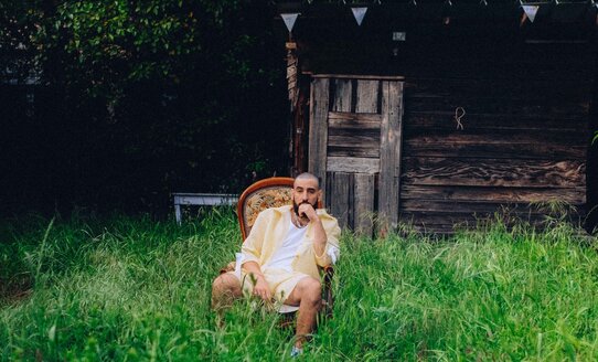 Ein Musiker sitzt in einem Garten | © Tanguy Delavet
