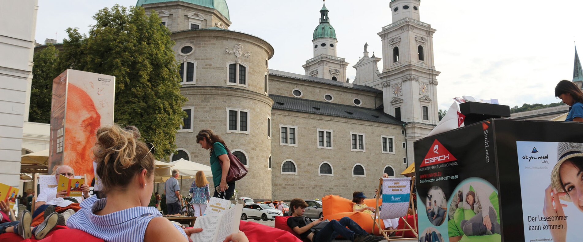Eine Dame liest in einem Sitzsack am Mozartplatz mit Blick auf den Salzburger Dom ein Buch. | © Innovationswerkstatt - Salzburg im Lesefieber 