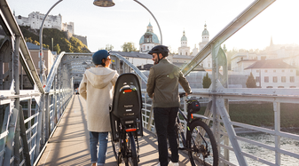 Eine Frau und ein Mann schieben Fahrräder über den Mozartsteg in der Altstadt Salzburg | © Niko Zuparic