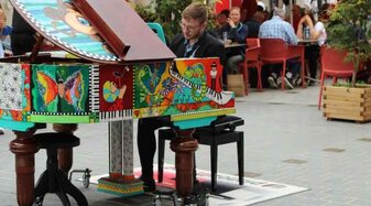 Ein Mann spielt auf einem bunt bemalten Klavier | © Alexander Gotter