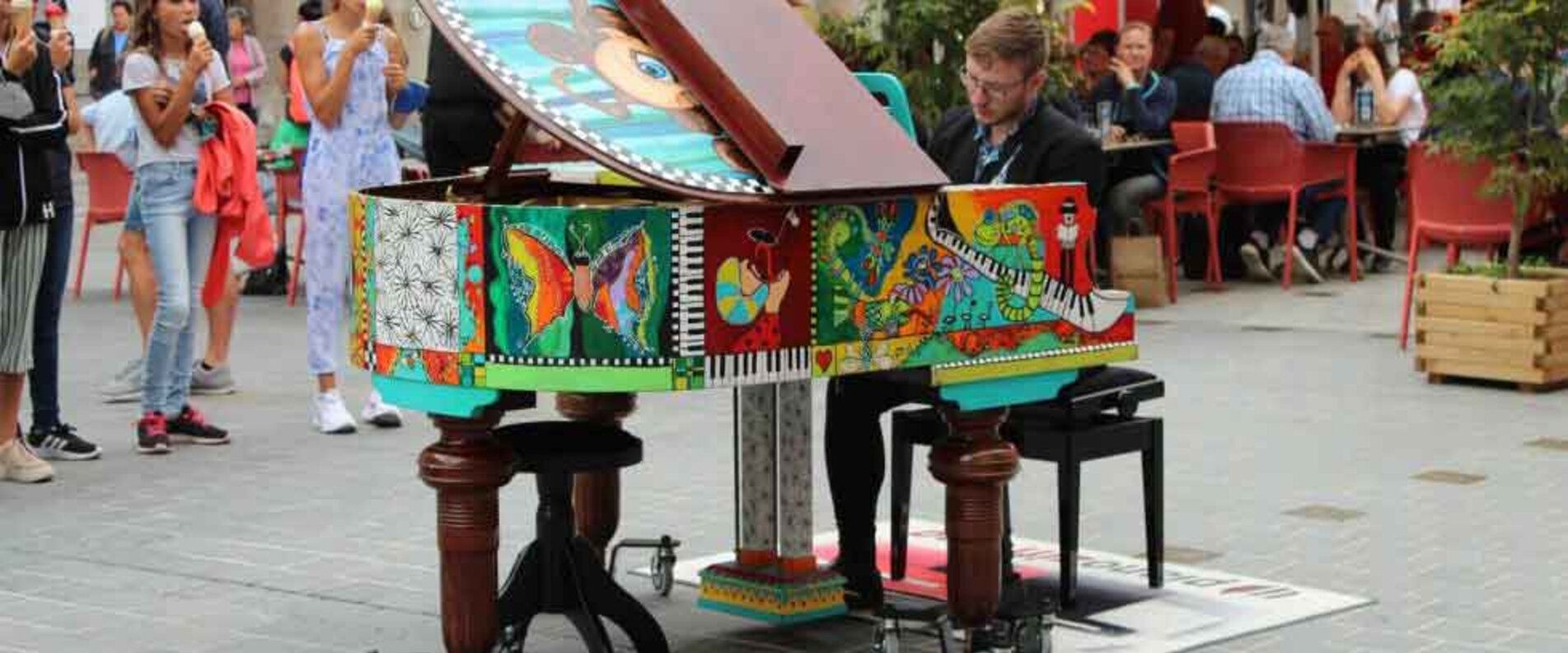 Ein Mann spielt auf einem bunt bemalten Klavier | © Alexander Gotter