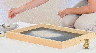 Eine Frau spielt mit Sand | © Salzburg Museum/Ortrun Heisler